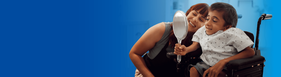 Young boy in a wheelchair smiling at a mirror